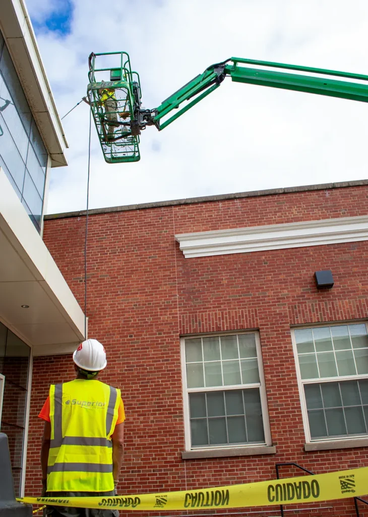 Superior Labor Solutions Employee On Cherry Picker Outside of Construction Site for Power Washing