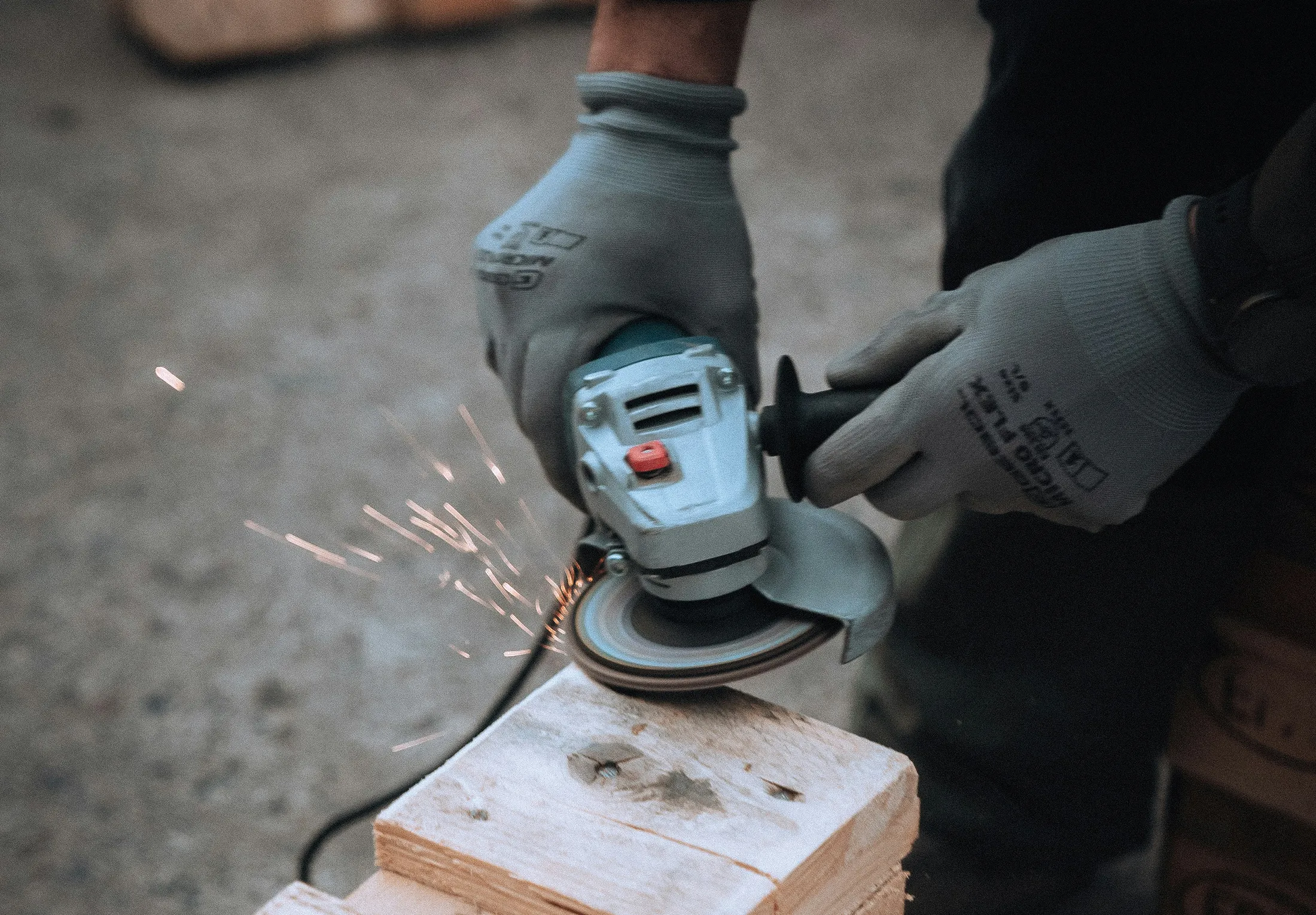 Construction Laborer Using Orbit Sander on Block of Wood